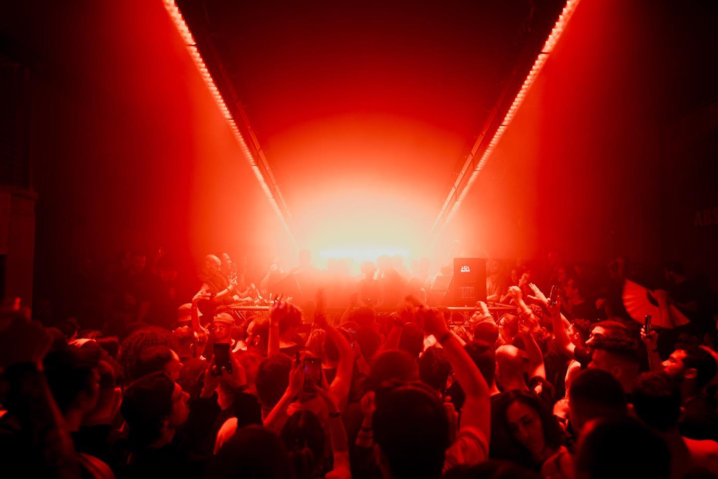 A crowd inside Oddity Club beneath linear ceiling lighting in a FOS lighting-installation photograph.
