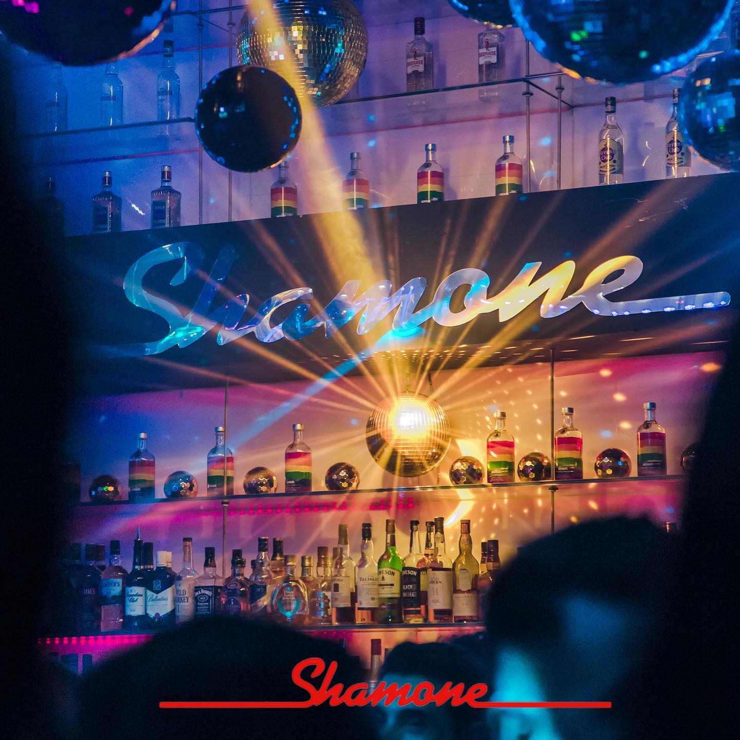 The Shamone bar with its illuminated name, mirrored disco balls and bottle display; the original photograph includes Shamone branding.