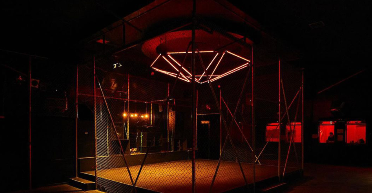 SMUT Athens interior with metal mesh partitions, raised platforms and angular red lighting.
