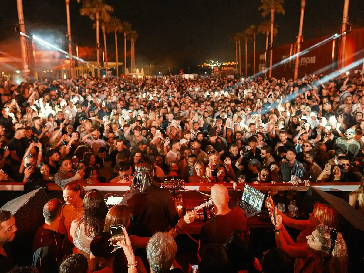 Crowd beneath the palms during a Pacha ICONS night at Playa Pacha