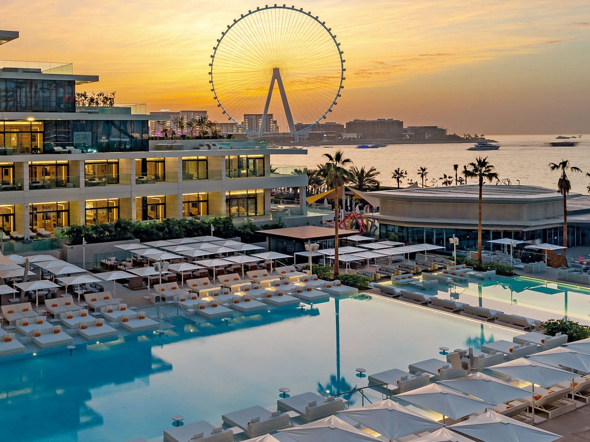 Playa Pacha pools and sunbeds with Ain Dubai at sunset